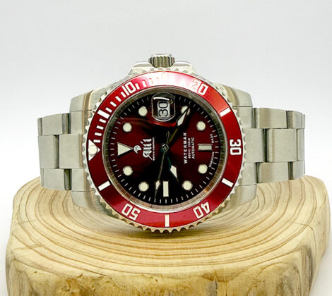 Ali'i Watch Company Waterman watch with a red dial and bezel sits on a piece of wood.