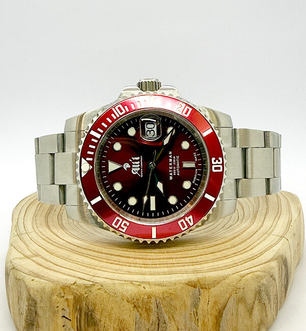 Ali'i Watch Company Waterman watch with a red dial and bezel sits on a piece of wood.
