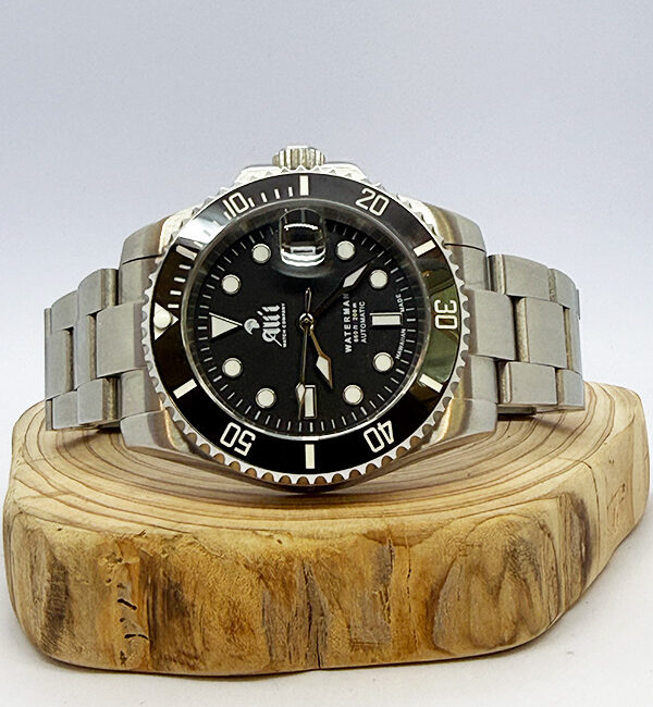 Ali'i Watch Company Waterman dive watch with a black dial and bezel sits on a piece of wood.