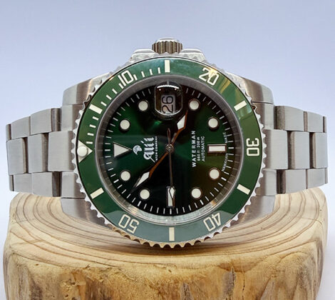 Ali'i Watch Company Waterman watch with a green dial and bezel sits on a piece of wood.