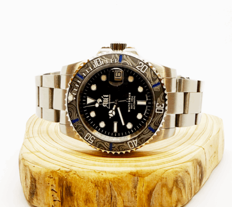 Ali'i Watch Company Waterman watch with a black bezel and carbon fiber bezel with blue minute markers sits on a piece of wood.
