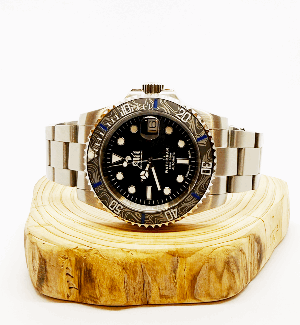 Ali'i Watch Company Waterman watch with a black bezel and carbon fiber bezel with blue minute markers sits on a piece of wood.