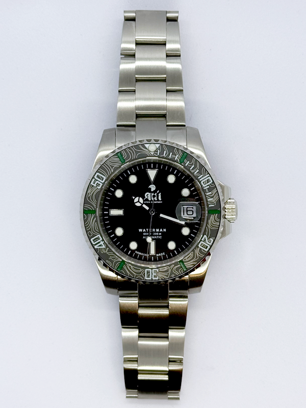 Front view of the Ali'i Watch Company Waterman watch with black dial and black carbon fiber bezel with green minute markers.