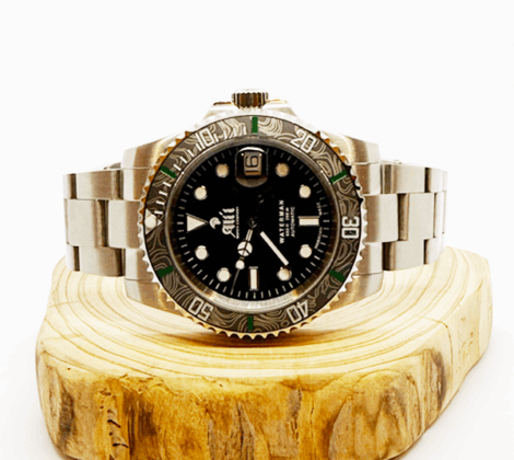 Ali'i Watch Company Waterman watch with a black bezel and carbon fiber bezel with green minute markers sits on a piece of wood.