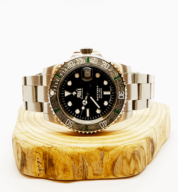 Ali'i Watch Company Waterman watch with a black bezel and carbon fiber bezel with green minute markers sits on a piece of wood.