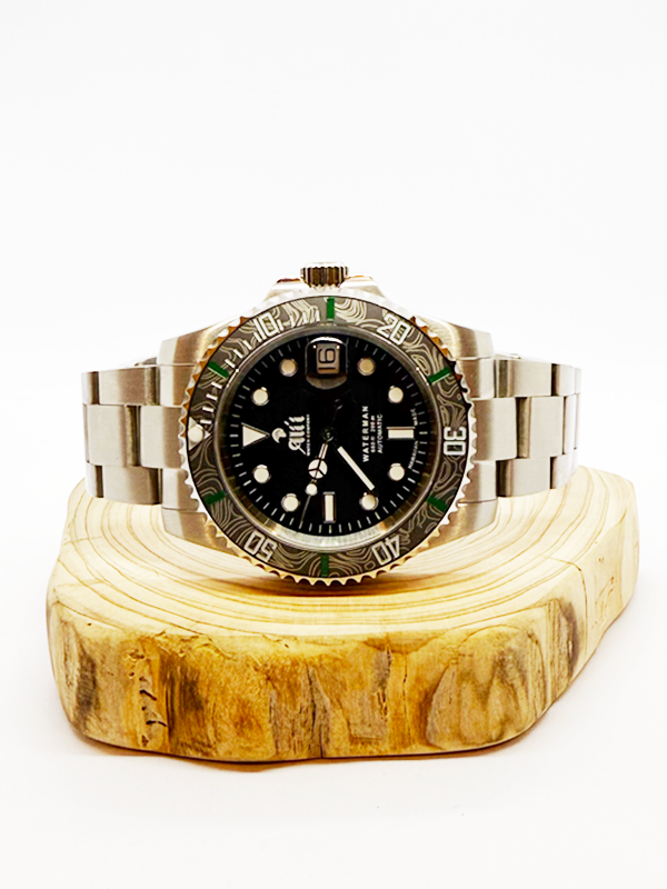Ali'i Watch Company Waterman watch with a black bezel and carbon fiber bezel with green minute markers sits on a piece of wood.