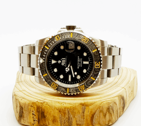Ali'i Watch Company Waterman watch with a black bezel and carbon fiber bezel with yellow minute markers sits on a piece of wood.