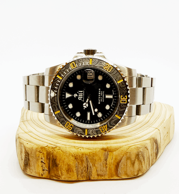 Ali'i Watch Company Waterman watch with a black bezel and carbon fiber bezel with yellow minute markers sits on a piece of wood.