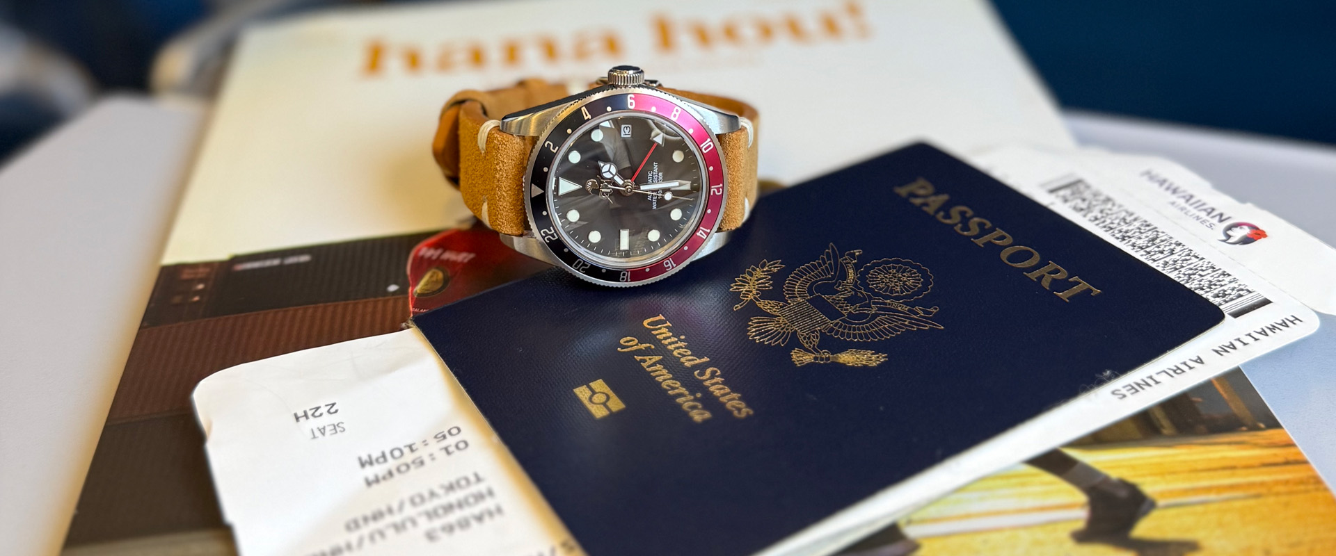 Waterman Voyager with a red and blue bezel rests on a passport on an airplane tray table.