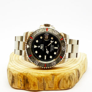 Ali'i Watch Company Waterman watch with a black bezel and carbon fiber bezel with red minute markers sits on a piece of wood.