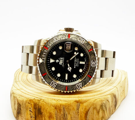 Ali'i Watch Company Waterman watch with a black bezel and carbon fiber bezel with red minute markers sits on a piece of wood.