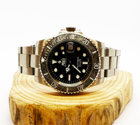 Ali'i Watch Company Waterman watch with a black bezel and carbon fiber bezel with silver minute markers sits on a piece of wood.