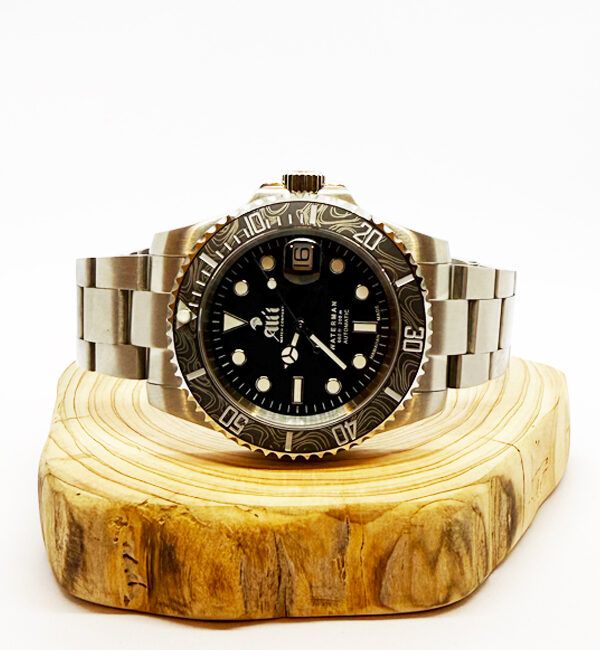 Ali'i Watch Company Waterman watch with a black bezel and carbon fiber bezel with silver minute markers sits on a piece of wood.