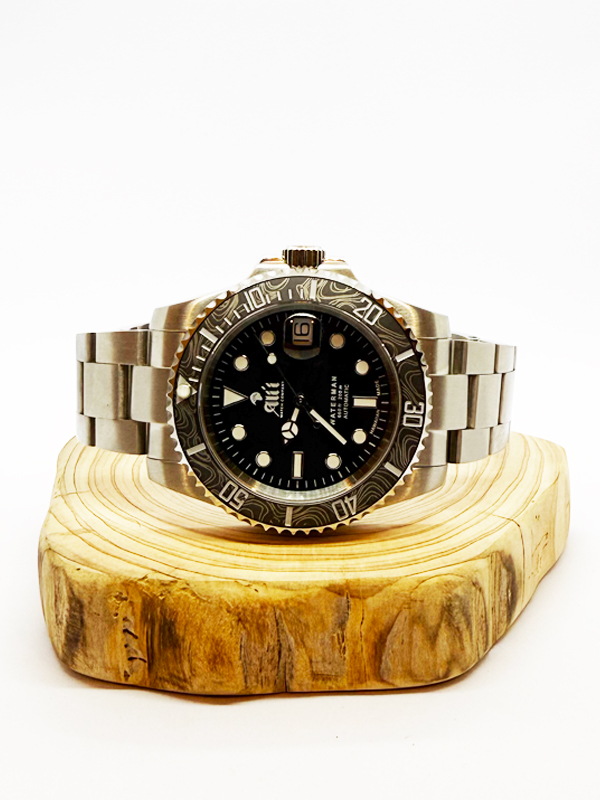 Ali'i Watch Company Waterman watch with a black bezel and carbon fiber bezel with silver minute markers sits on a piece of wood.