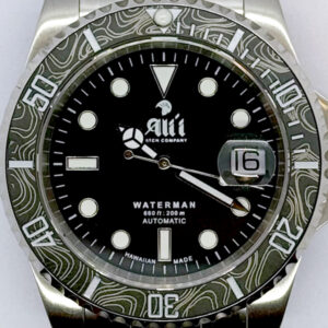 A close up of the dial on the Ali'i Watch Company Waterman watch with black dial and black carbon fiber bezel with silver minute markers.