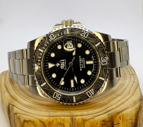 Ali'i Watch Company Waterman watch with a black bezel and carbon fiber bezel with silver minute markers sits on a piece of wood.