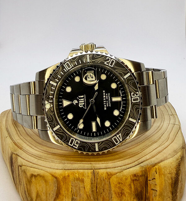 Ali'i Watch Company Waterman watch with a black bezel and carbon fiber bezel with silver minute markers sits on a piece of wood.