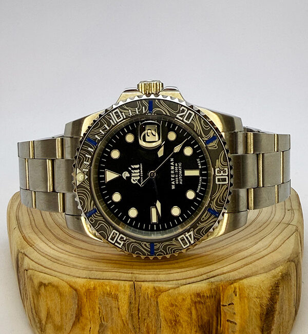 Ali'i Watch Company Waterman watch with a black bezel and carbon fiber bezel with blue minute markers sits on a piece of wood.