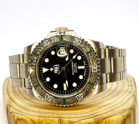 Ali'i Watch Company Waterman watch with a black bezel and carbon fiber bezel with green minute markers sits on a piece of wood.