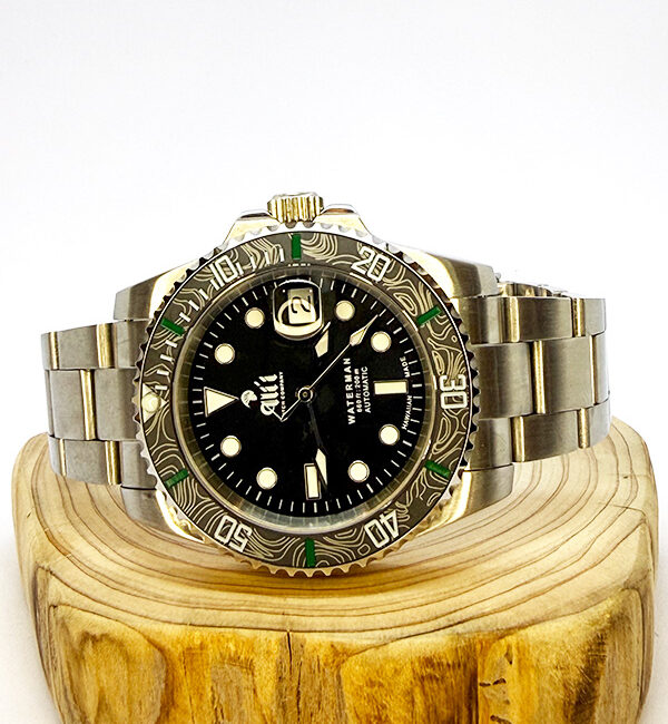 Ali'i Watch Company Waterman watch with a black bezel and carbon fiber bezel with green minute markers sits on a piece of wood.