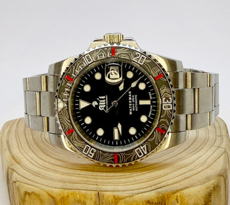 Ali'i Watch Company Waterman watch with a black bezel and carbon fiber bezel with red minute markers sits on a piece of wood.