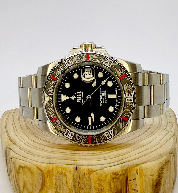 Ali'i Watch Company Waterman watch with a black bezel and carbon fiber bezel with red minute markers sits on a piece of wood.