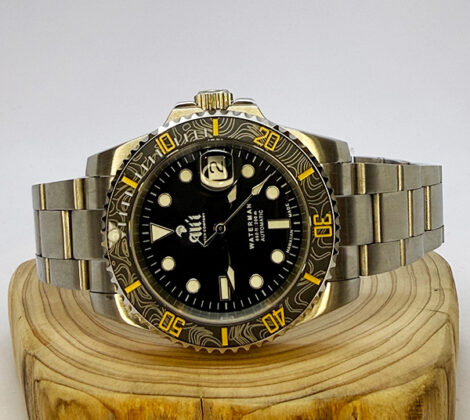 Ali'i Watch Company Waterman watch with a black bezel and carbon fiber bezel with yellow minute markers sits on a piece of wood.